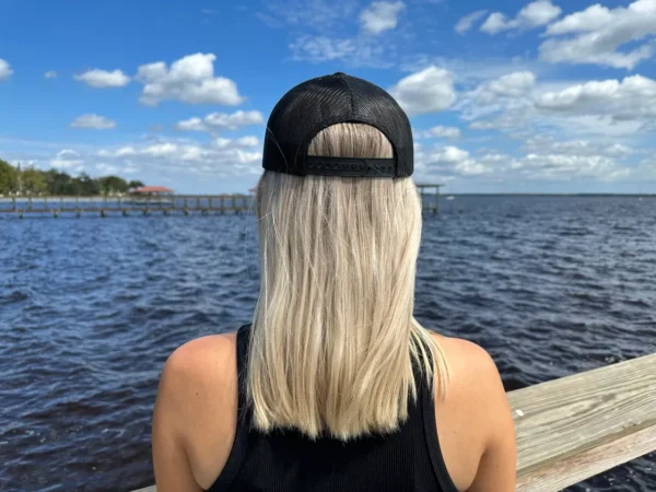 A woman with long blonde hair wearing a black hat.