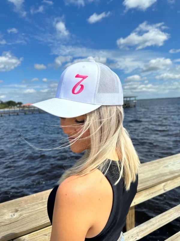 A woman wearing a hat standing on the pier.