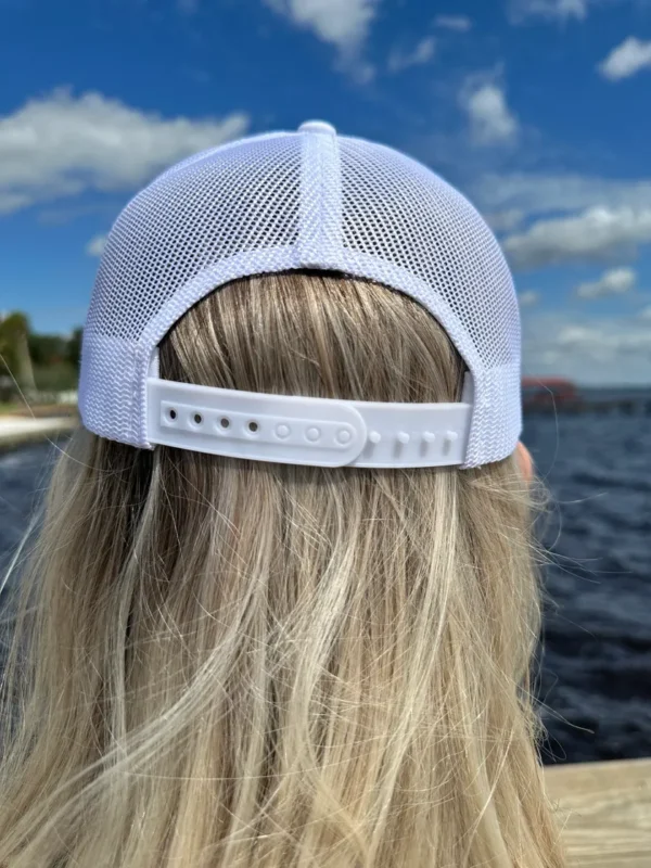 A woman with long blonde hair wearing a white hat.