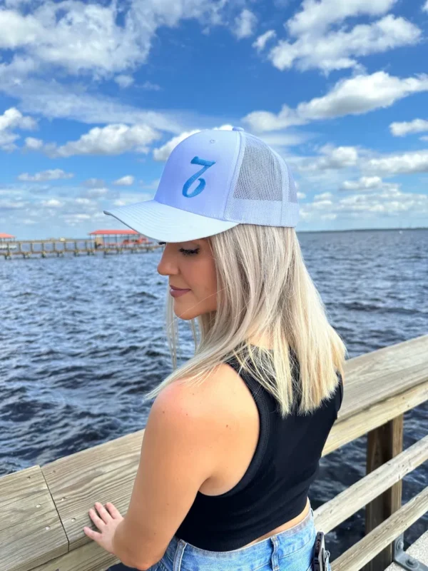 A woman wearing a hat sitting on the pier.